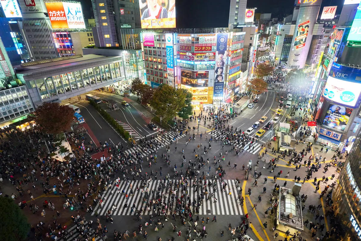 Shibuya crossing aerial view with large crowd crossing at night in Tokyo Japan