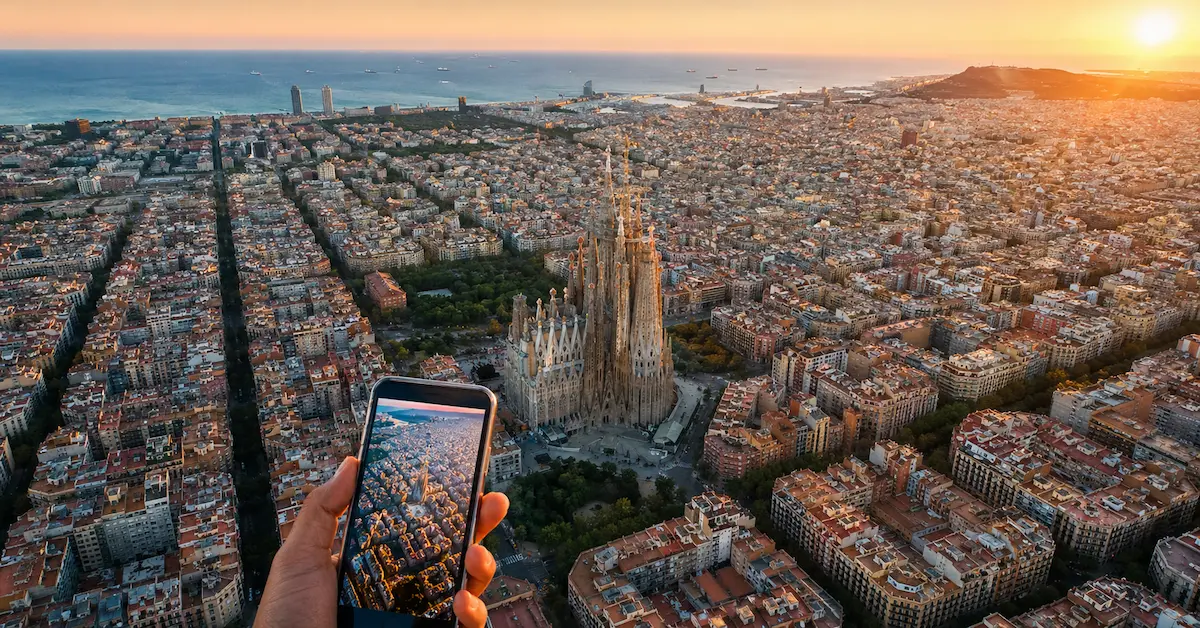 Barcelona aerial sunset with Sagrada Familia and smartphone showing city map, real connectivity experience in Spain 2026